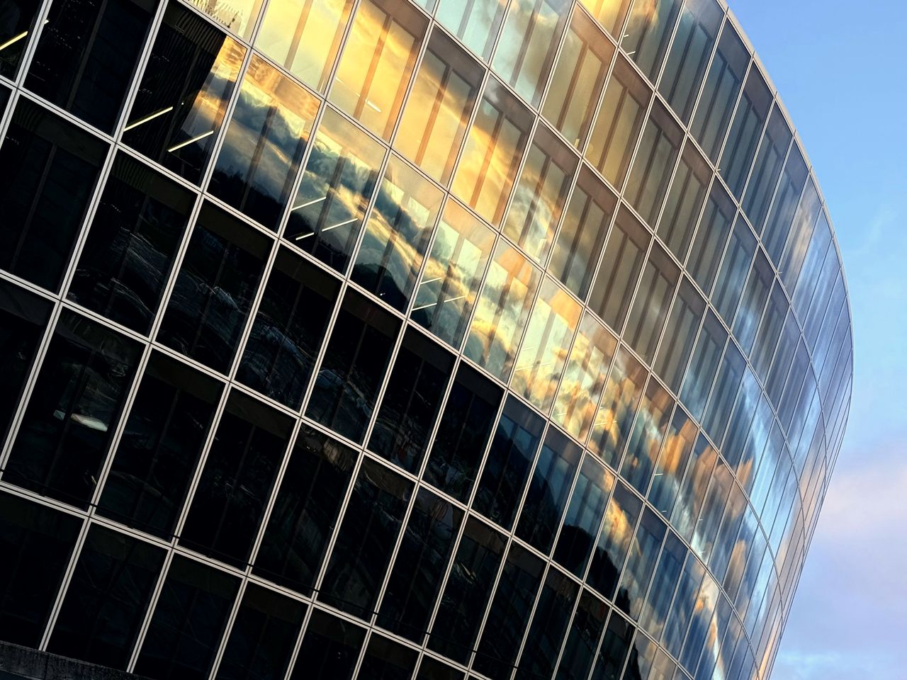 Torre de vidrio curva que refleja luz cálida