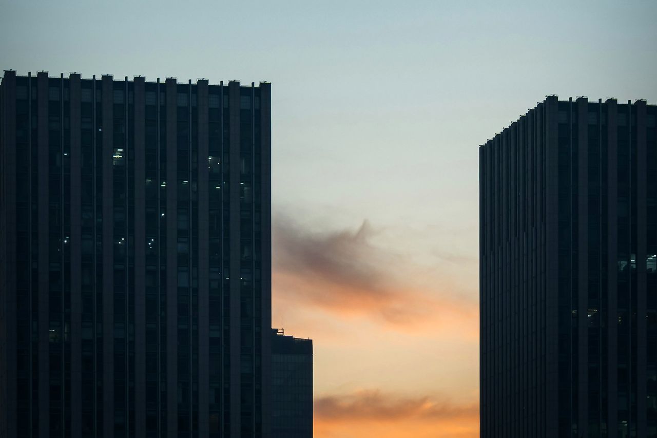 Dos torres de oficinas recortadas contra un cielo al atardecer